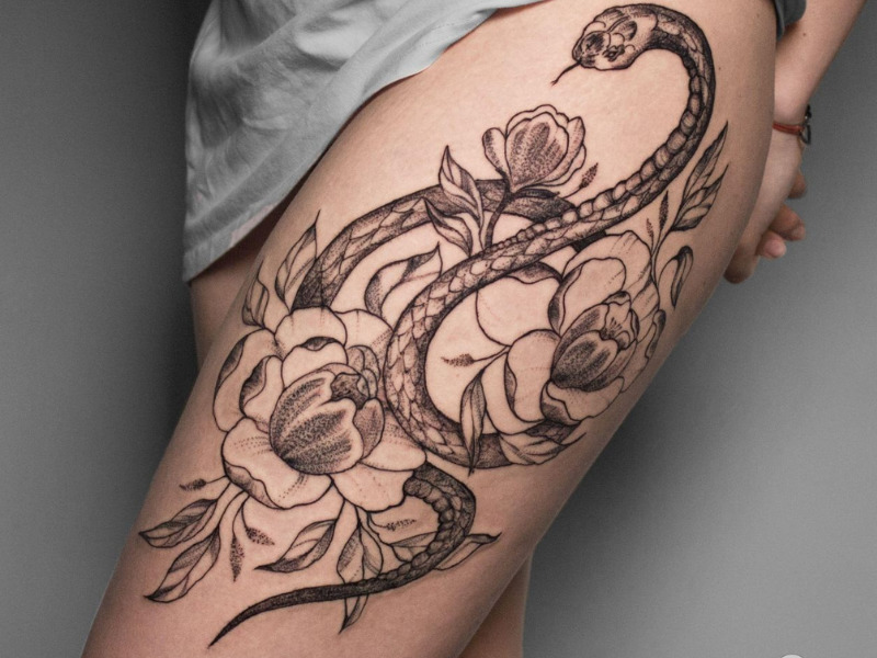 Large snake tattoo located on the thigh