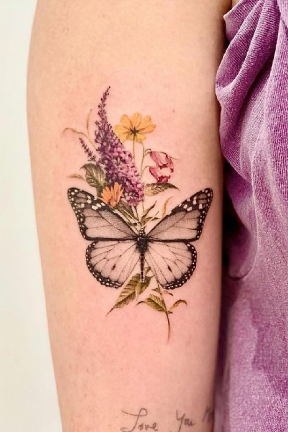 Black and grey butterfly tattoo with colorful yellow flowers on arm