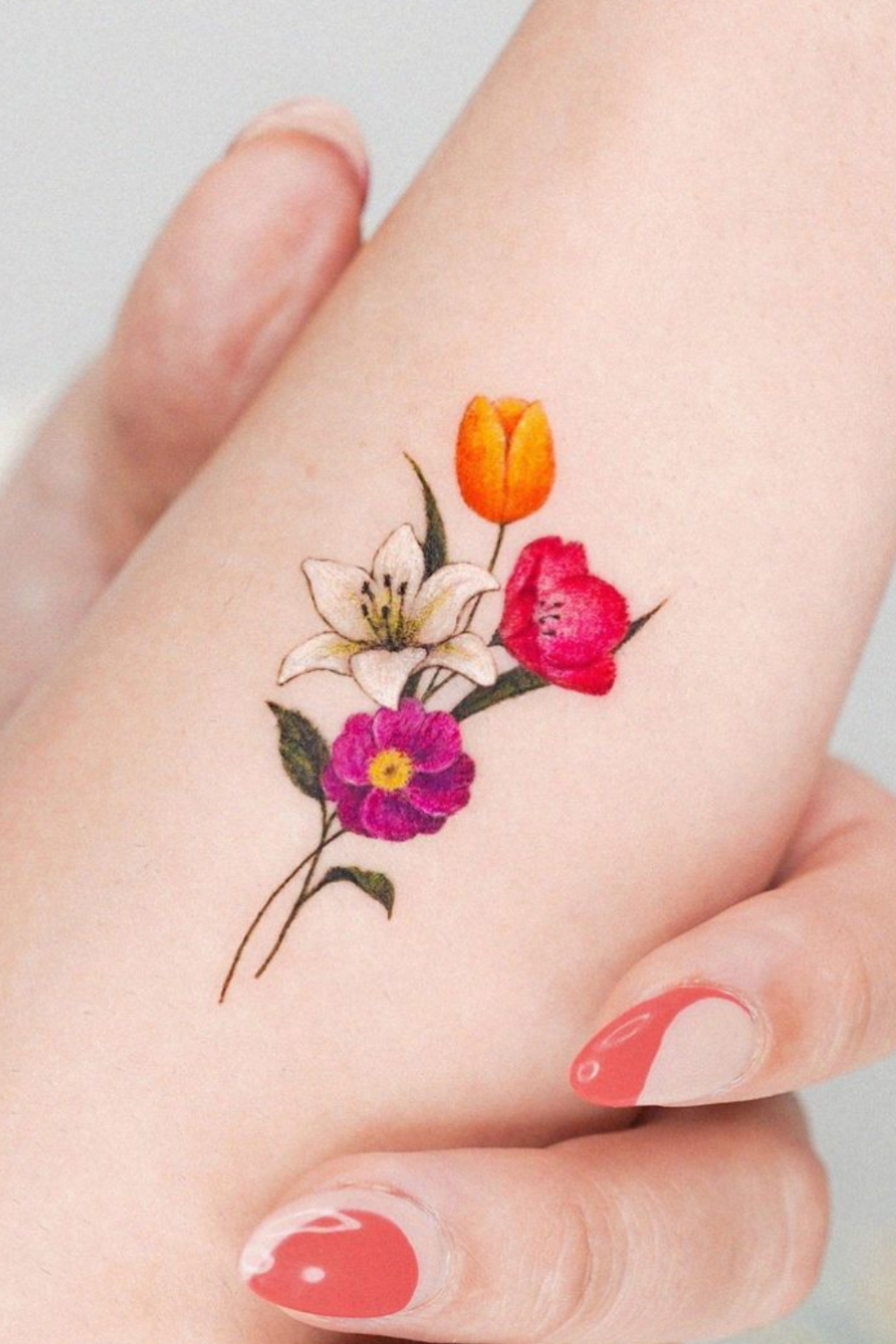 Small flower tattoo with pink, red and white flowers and yellow bud